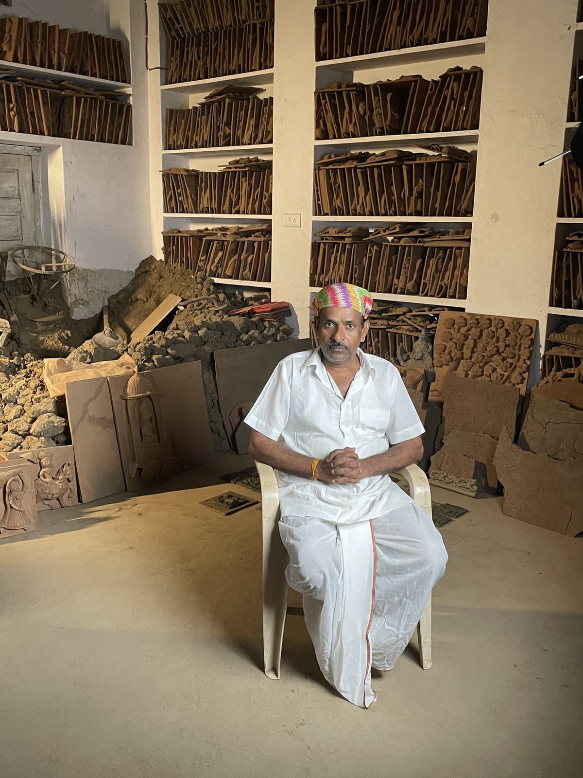 Master artisan Dinesh Chandra Kumhar hand-sculpting clay relief plaques on the studio floor in Molela