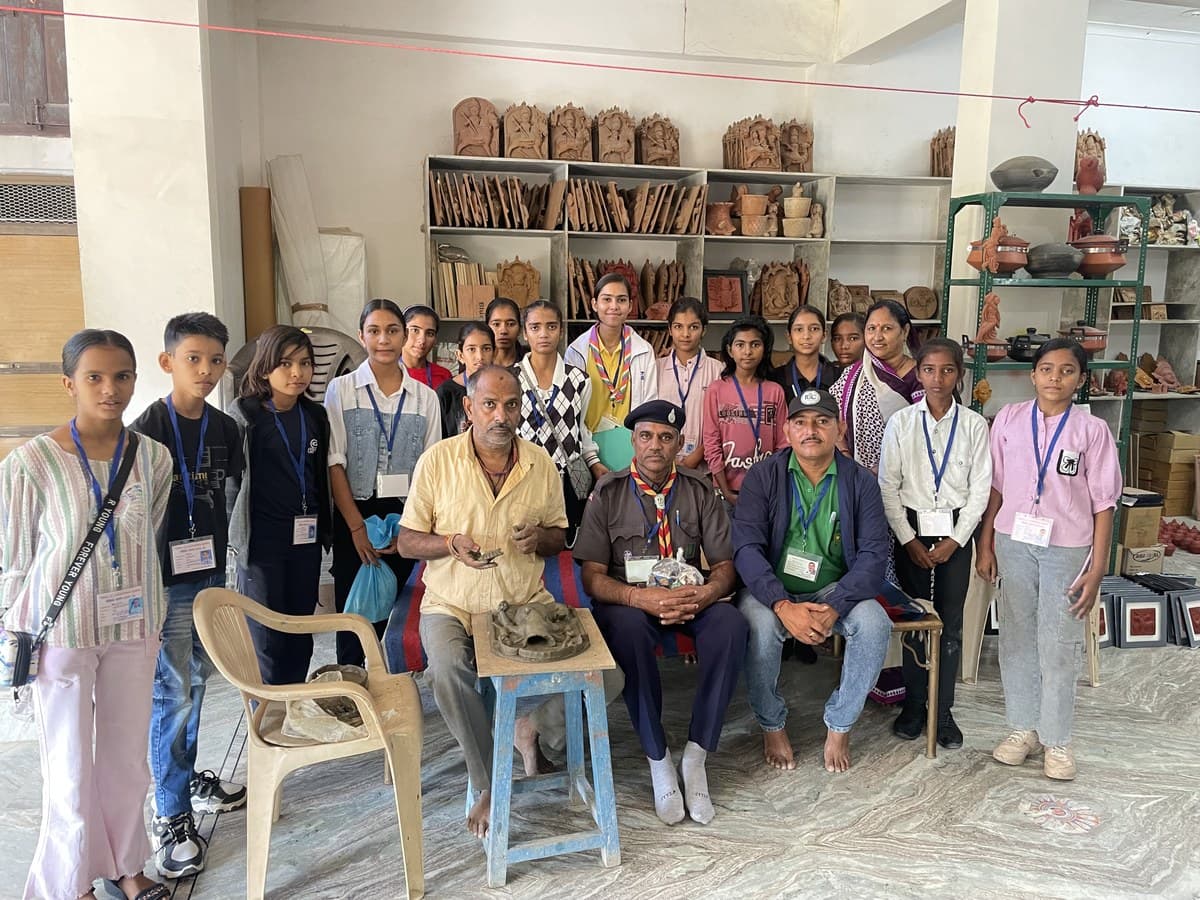 Community pottery workshop in Molela with Dinesh Chandra Kumhar, students, and scouts holding clay art