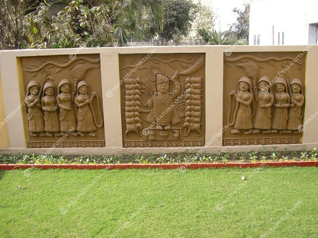 Three terracotta relief panels in a garden wall showing Shrinathji flanked by sacred cows and gopis