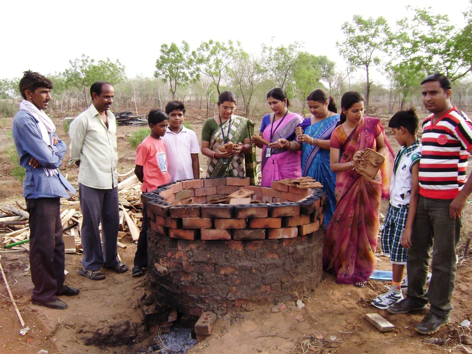 Traditional open-air bhatti kiln firing demonstration with master craftsmen, students, and participants