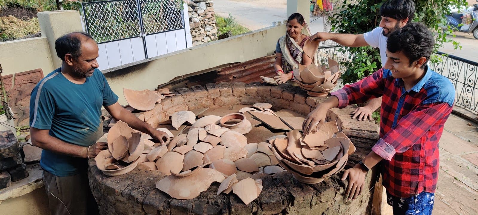 Artisans loading the traditional circular pit kiln (bhatti) covered with broken pottery shards and clay in Rajasthan