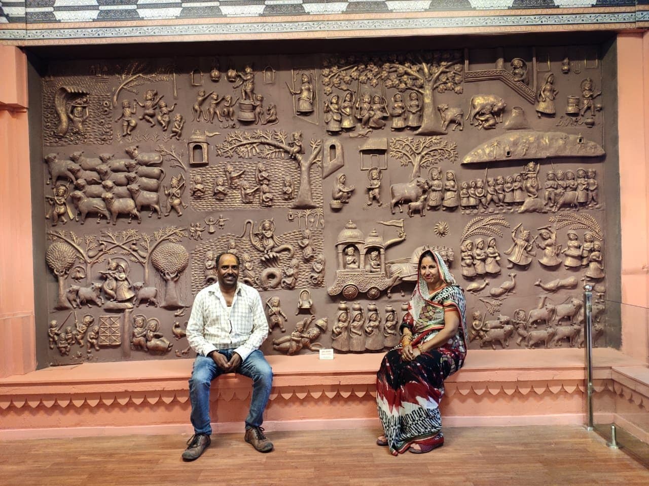 Dinesh Chandra Kumhar and Kailash Devi seated before their Krishna Leela terracotta mural