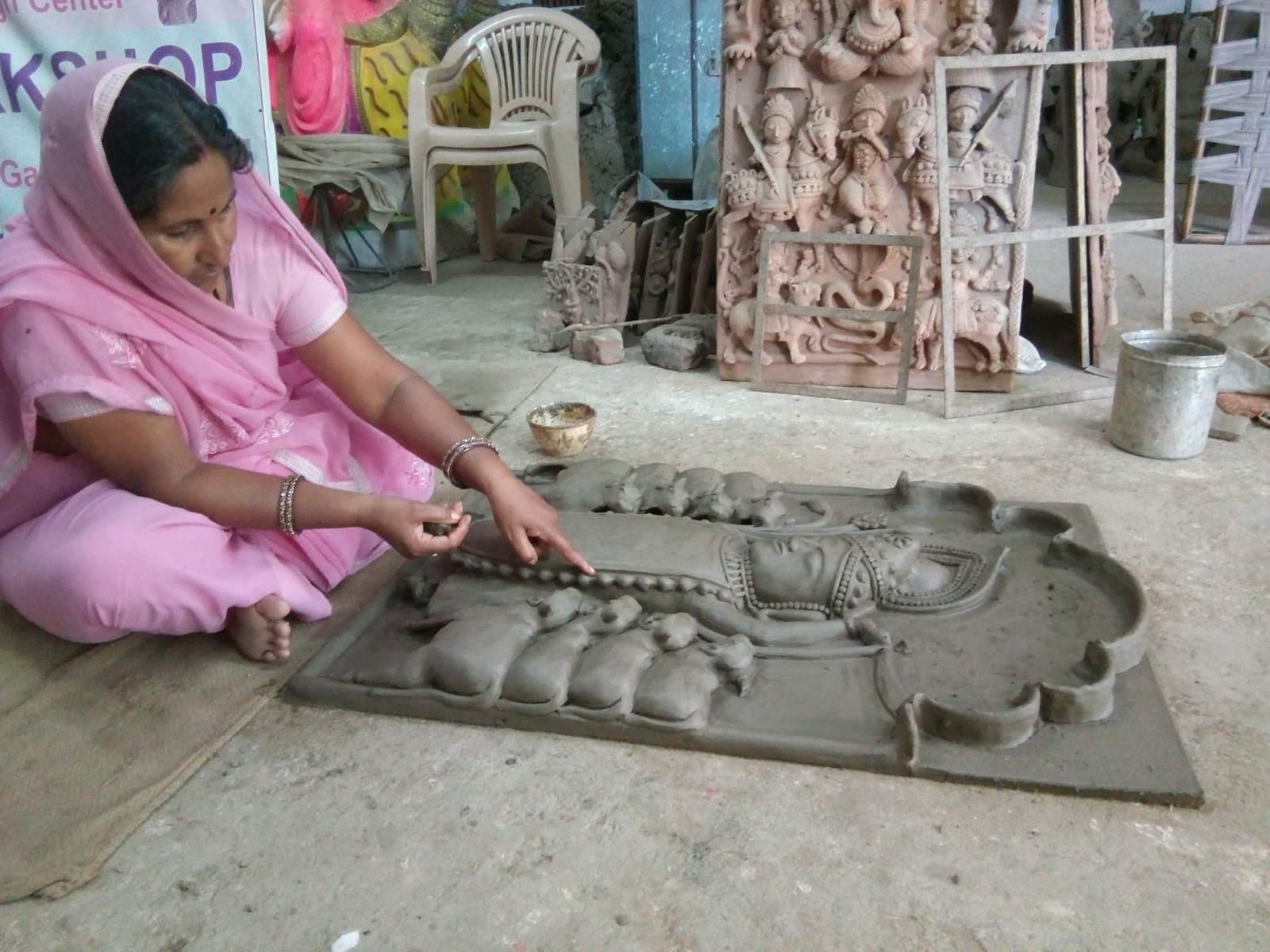 Kailash Devi hand-sculpting a traditional Devnarayan votive plaque on the studio floor