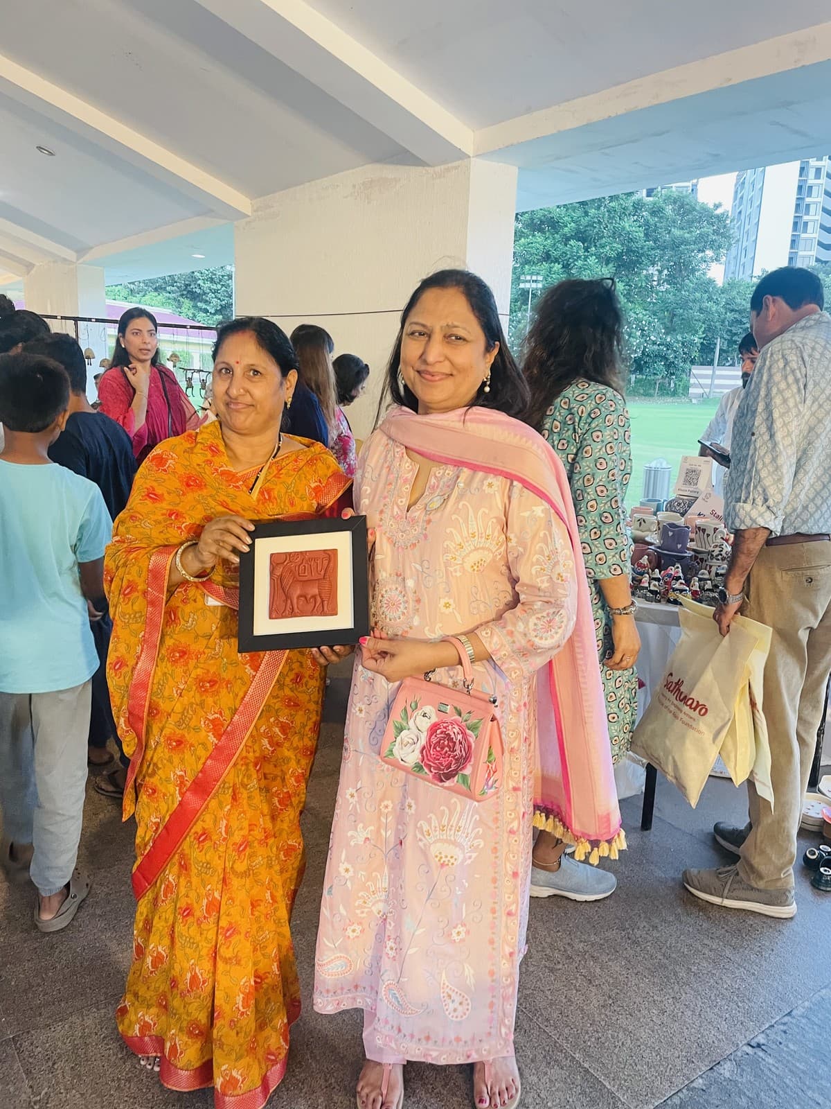 Kailash Devi presenting a framed terracotta relief artwork to an art patron at a national craft exhibition